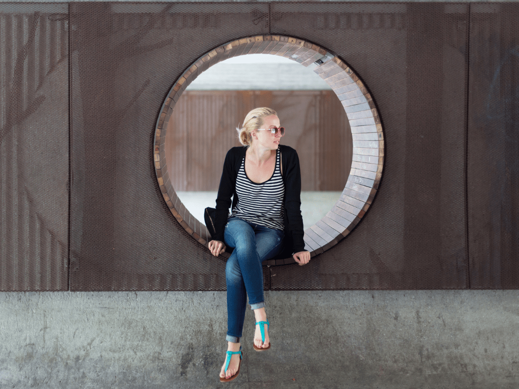 Frau sitzt in einer runden Öffnung und blickt zur Seite