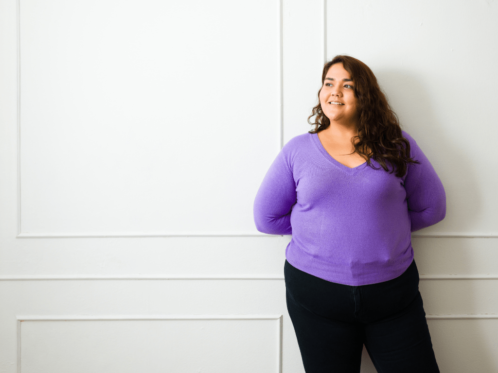 Frau steht ruhig vor einer weißen Wand und blickt zur Seite