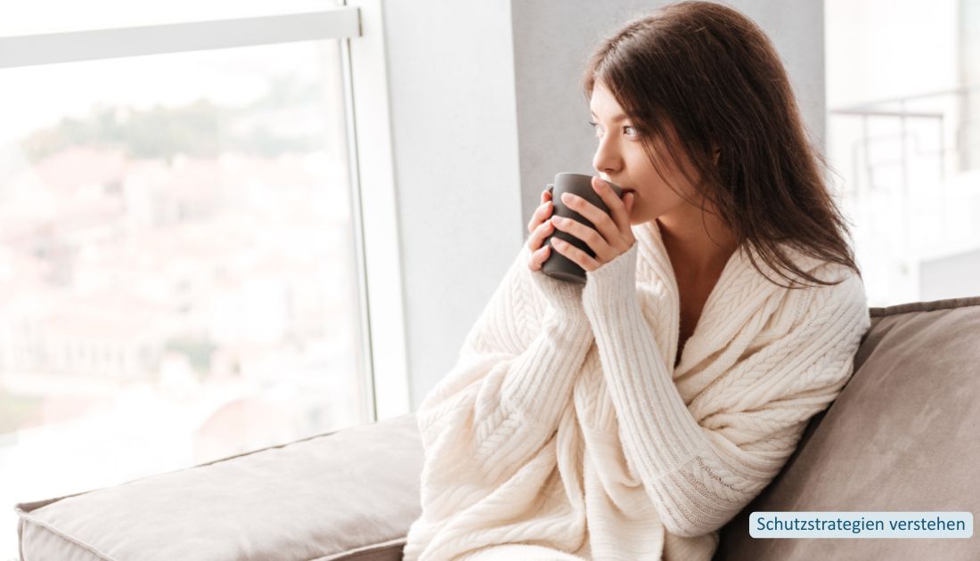 Schutzstrategien verstehen Frau sitzt mit einer Tasse am Fenster und blickt nach draußen.